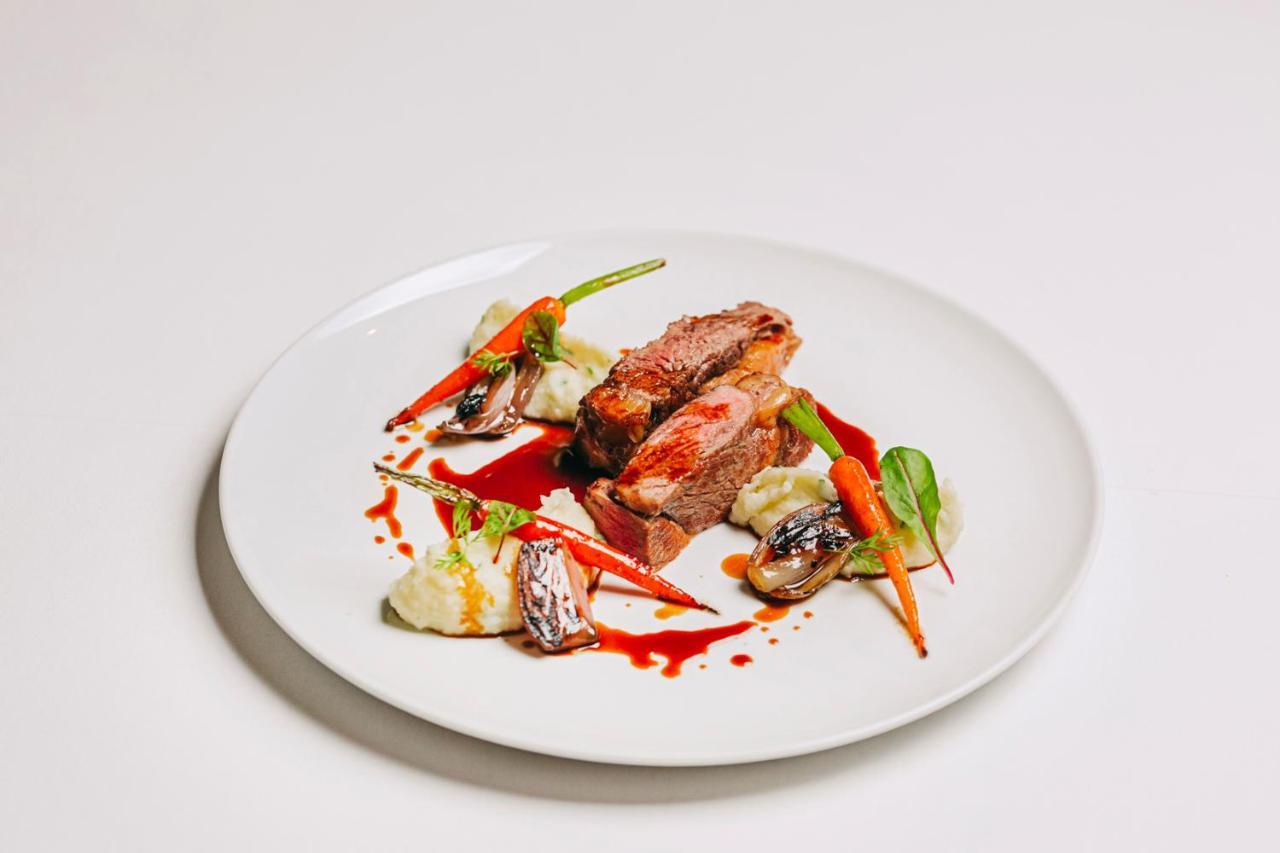 Ap Lago Montargil - Conference & Spa Extérieur photo The photo features a beautifully plated dish. At the center, there are slices of a tender meat, likely beef, showcasing a juicy pink interior. Accompanying the meat are several elements: vibrant orange carrots, perhaps roasted or glazed, and dollops 