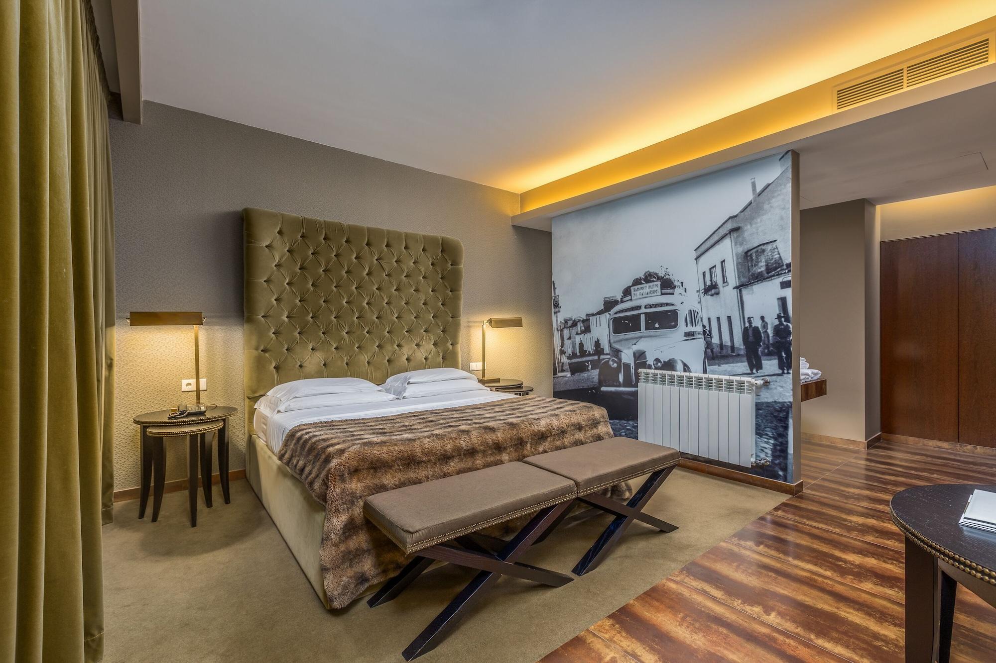 Ap Lago Montargil - Conference & Spa Extérieur photo The photo shows a modern hotel room featuring a king-sized bed with a tufted headboard, dressed in white linens and a decorative throw blanket. On either side of the bed, there are bedside tables with lamps. The room is well-lit, with an ambient ceil
