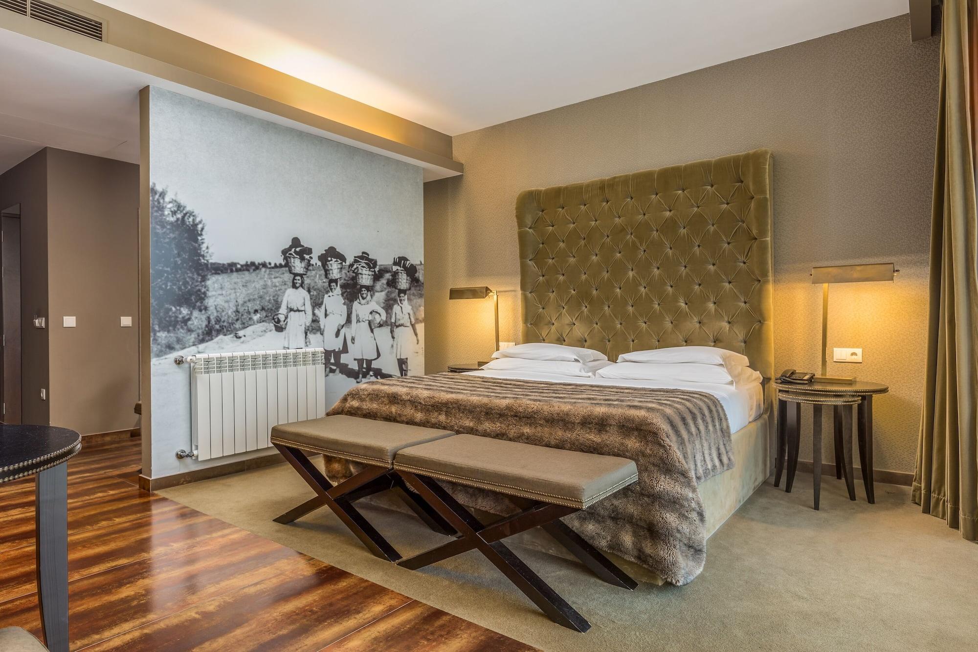 Ap Lago Montargil - Conference & Spa Extérieur photo The photo shows a modern hotel room with a large, plush bed that has a tufted, green headboard. The bedding is white with a textured blanket at the foot of the bed. A decorative wall behind the bed features a black and white mural of children in a fi